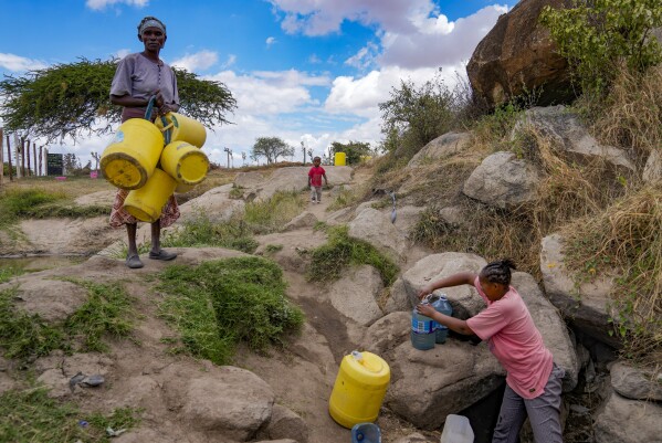 Joyce Ngui, left, fetches groundwater in Athi River, Machakos county, Kenya, Tuesday, Oct. 17, 2023. “Sometimes, we get to the water vending stations and find that the queue is long and then the water finishes and you have to wait,” Ngui said. “Most of the times you don’t have money to buy even the salty water sold around. So we have no choice but to use the swamp water," she said. (AP Photo/Brian Inganga)