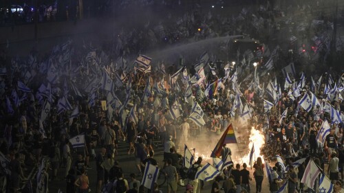 Israeli police use a water cannon to disperse demonstrators blocking the freeway during protest against plans by Prime Minister Benjamin Netanyahu's government to overhaul the judicial system in Tel Aviv, Israel, Wednesday, July 5, 2023. Protesters took to the streets in support of Tel Aviv's police chief, who announced his resignation on Wednesday. (AP Photo/Oded Balilty)