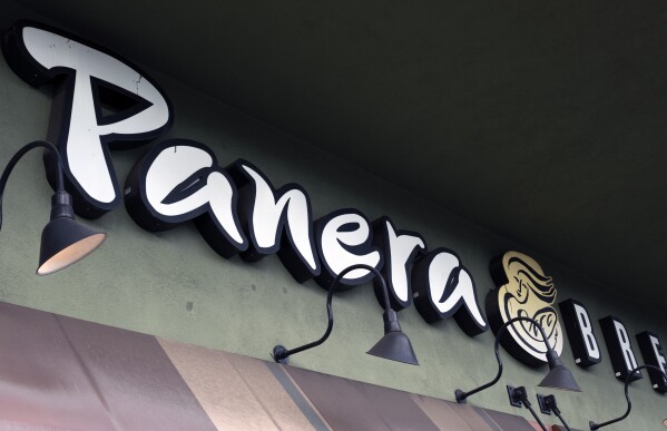 FILE - A Panera Bread sign and logo is attached to the outside of a Panera Bread restaurant location in Los Angeles, Thursday, March 7, 2024. As California prepares to enforce a new $20-per-hour minimum wage for fast food workers, an unusual exemption for eateries that bake their own bread has come under scrutiny. (AP Photo/Richard Vogel, File)