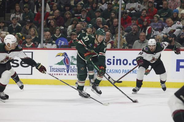 Minnesota Wild left wing Kirill Kaprizov (97) handles the puck against Arizona Coyotes center Nick Bjugstad (17) and defenseman J.J. Moser (90) during the first period of an NHL hockey game Sunday, Nov. 27, 2022, in St. Paul, Minn. (AP Photo/Stacy Bengs)