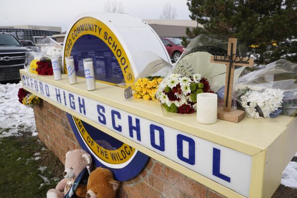 FILE - Memorial items are shown on the sign of Oxford High School in Oxford, Mich., Wednesday, Dec. 1, 2021. Officials planned to welcome students back to Oxford High School on Monday, Jan. 24, 2022, which is reopening for the first time since four students were killed and six students and a teacher were injured during a shooting at the school on Nov. 30, 2021. The students have been attending classes at other buildings since Jan. 10. A fellow student, Ethan Crumbley, 15, is charged with murder and other crimes. His parents also are facing charges. (AP Photo/Paul Sancya, File)