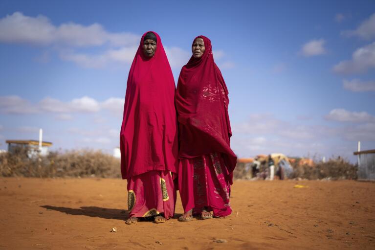 Abdiyo Barre Ali, right and Abdiyo Ali Abdi recite poetry at a camp for displaced people on the outskirts of Dollow, Somalia, on Wednesday, Sept. 21, 2022.  Somalia is in the midst of the worst drought anyone there can remember. A rare famine declaration could be made within weeks. Climate change and fallout from the war in Ukraine are in part to blame. (AP Photo/Jerome Delay)