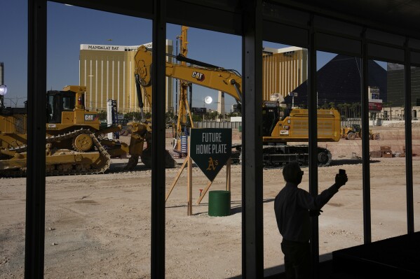 A person takes a picture near construction equipment during a groundbreaking ceremony for the Athletics' baseball stadium Monday, June 23, 2025, in Las Vegas. (AP Photo/John Locher)