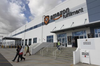 FILE - People leave the entrance to the Amazon San Bernardino Fulfillment Center, October 29, 2013 in San Bernardino, Calif. California has hit Amazon with two separate fines totaling $5.9 million, alleging the e-commerce giant violated a law designed to protect warehouse employees from requirements that they work so quickly that it risks their safety, officials said Tuesday, June 18, 2024. (AP Photo/David McNew, File)