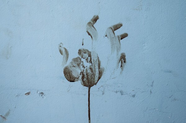 The figure of a hand is marked with blood on the wall of a bomb shelter located in the Thai workers' housing section of Kibbutz Nir Oz, Israel, near the Gaza Strip, Thursday, Nov. 9, 2023. The kibbutz was attacked on Oct. 7 by Hamas militants, who killed and kidnapped members of its community. (AP Photo/Bernat Armangue)