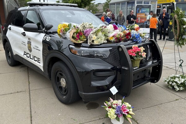FILE - Mourners leave flowers on a police car at a precinct, May 31, 2024, a day after an officer and two others were killed in a shooting. A fourth person has died from injuries sustained in a late May mass shooting in Minneapolis that also killed a police officer. Mohamed Aden, 36, of Columbia Heights, died Friday from complications of multiple gunshot wounds he sustained in the May 30 shooting, the Hennepin County Medical Examiner’s Office said Sunday, June 9 in a news release. (AP Photo/Mark Vancleave, file)