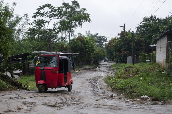 A three-wheeled motorized taxi drives along a dirt road on the outskirts of San Pedro Sula, Honduras, Monday, Dec. 9, 2024. (AP Photo/Moises Castillo)