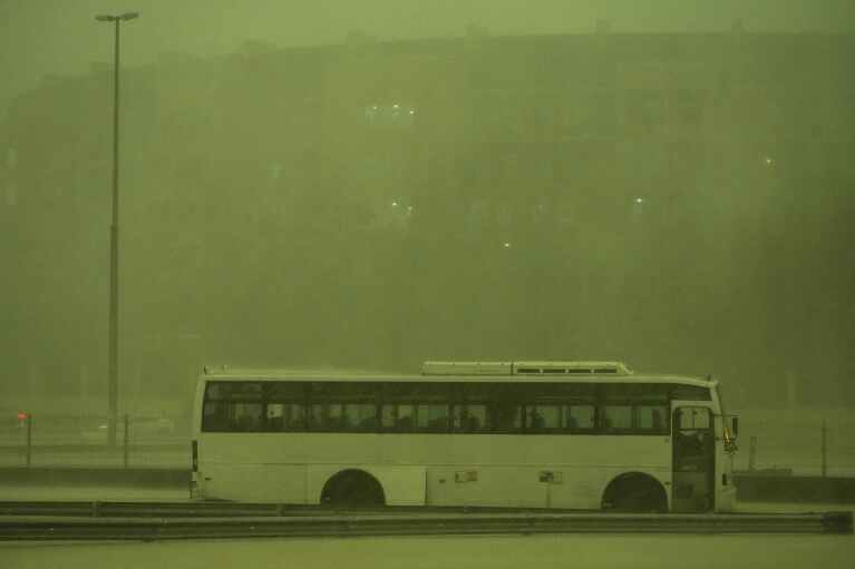 A bus stands abandoned in pouring rain as the sky turned green as a storm hit in Dubai, United Arab Emirates, Tuesday, April 16, 2024. Heavy rains lashed the United Arab Emirates on Tuesday, flooding out portions of major highways and leaving vehicles abandoned on roadways across Dubai. Meanwhile, the death toll in separate heavy flooding in neighboring Oman rose to 18 with others still missing as the sultanate prepared for the storm. (AP Photo/Jon Gambrell)