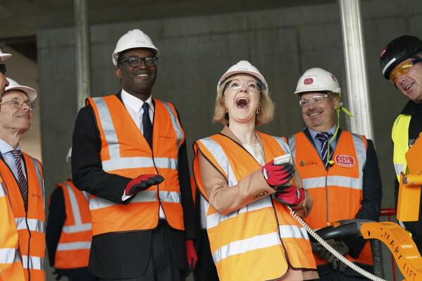 Britain's Prime Minister Liz Truss, centre right and Chancellor of the Exchequer Kwasi Kwarteng react during a visit to a construction site for a medical innovation campus, on day three of the Conservative Party annual conference at the International Convention Centre in Birmingham, England, Tuesday, Oct. 4, 2022. (Stefan Rousseau/Pool Photo via AP)