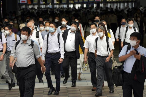 FILE - In this July 12, 2021, file commuters wearing face masks walk in a passageway during a rush hour at Shinagawa Station in Tokyo. Tokyo recorded 1,979 new COVID-19 cases Thursday, hitting a new six-month high one day before the Olympics are to begin amid growing worry about the worsening infections during the games. (AP Photo/Eugene Hoshiko, File)