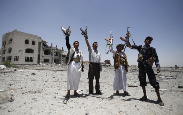 FILE - Shiite fighters, known as Houthis, hold up their weapons as they chant slogans at the residence of a military commander of the Houthi militant group, destroyed by a Saudi-led airstrike in Sanaa,, Yemen, Tuesday, April 28, 2015. (AP Photo/Hani Mohammed, File)