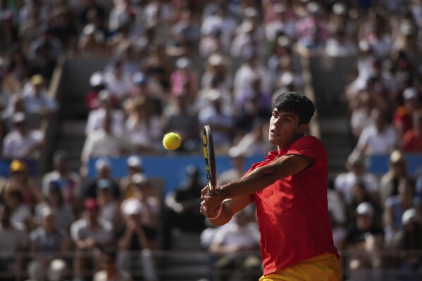 Spain's Carlos Alcaraz backhands to Serbia's Novak Djokovic during the men's singles tennis final at the Roland Garros stadium during the 2024 Summer Olympics, Sunday, Aug. 4, 2024, in Paris, France. (AP Photo/Louise Delmotte)