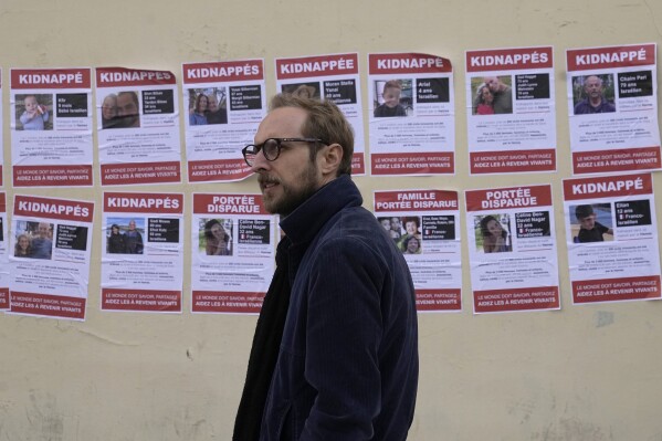 A man walks past posters pasted by the UEJF (Union of Jewish French Students) Monday, Oct. 16, 2023 in Paris. The images across Paris show of Jewish missing persons held by Hamas in Gaza. (AP Photo/Michel Euler)