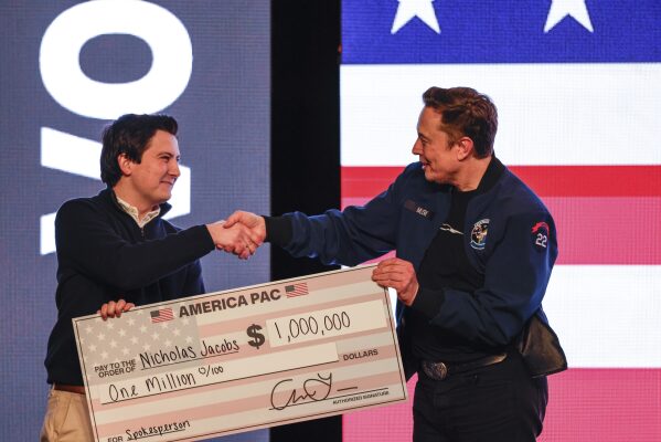 Elon Musk presents a check for $1 million dollars to a man during a town hall March 30, 2025, in Green Bay, Wis. (AP Photo/Jeffrey Phelps, File)