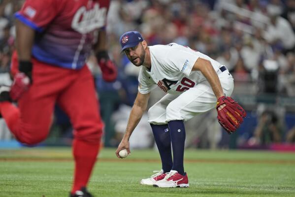 U.S. pitcher Adam Wainwright (50) attempts to throw out Cuba's Alfredo Despaigne at first during the third inning of a World Baseball Classic game, Sunday, March 19, 2023, in Miami. Despaigne advanced from first to second on a throwing error by Wainwright. (AP Photo/Wilfredo Lee)