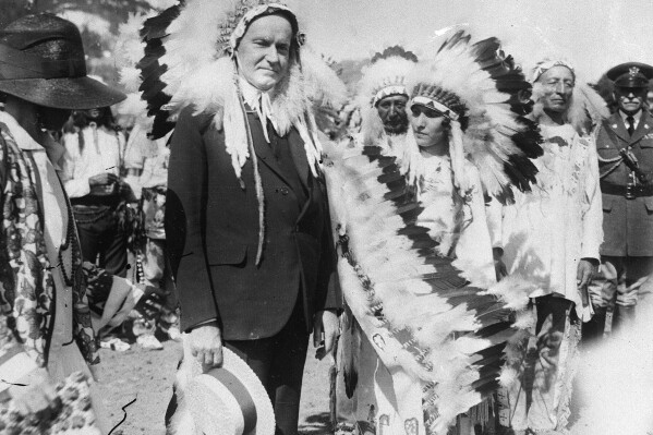 FILE - U.S. President Calvin Coolidge wears a Native American headdress of the Sioux tribe as he is adopted as Chief Leading Eagle and first white chief of the tribe at the celebration of the 51st anniversary of the settlement of Deadwood, South Dakota, in 1927. Coolidge signed the Indian Citizenship Act of 1924. (AP Photo/File)