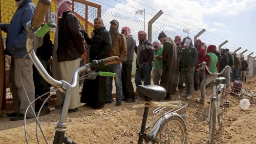 FILE - Syrian refugees line up to register their names at an employment office, Feb. 18, 2018, at the Azraq Refugee Camp, 100 kilometers (62 miles) east of Amman, Jordan. The United Nations food agency said Tuesday, July 18, 2023, that it will reduce monthly cash aid for 120,000 Syrian refugees living in camps in Jordan because of what it described as an “unprecedented funding crisis.” (AP Photo/Raad Adayleh, File)