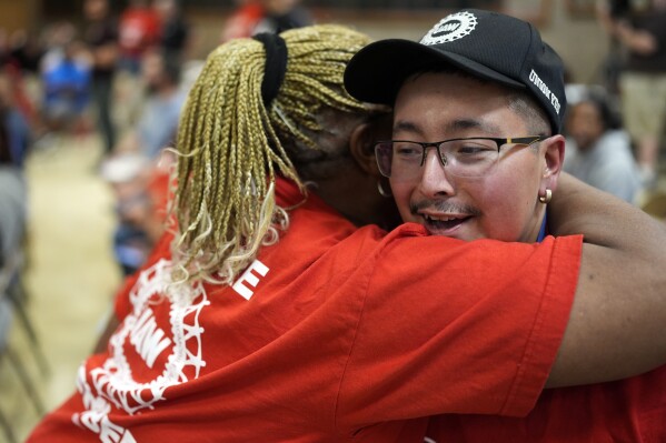 Volkswagen automobile plant employee Duke Brandon, right, hugs Vicky Holloway as they watch the results of a UAW union vote, late Friday, April 19, 2024, in Chattanooga, Tenn. (AP Photo/George Walker IV)