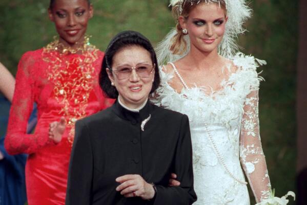FILE - Japanese fashion designer Hanae Mori, center, is applauded by models after the presentation of her 1997-98 fall-winter haute couture collection presented in Paris, July 9, 1997. Mori, known for her elegant signature butterfly motifs, has died, according to the Hanae Mori Office. She was 96. (AP Photo/Michel Lipchitz, File)