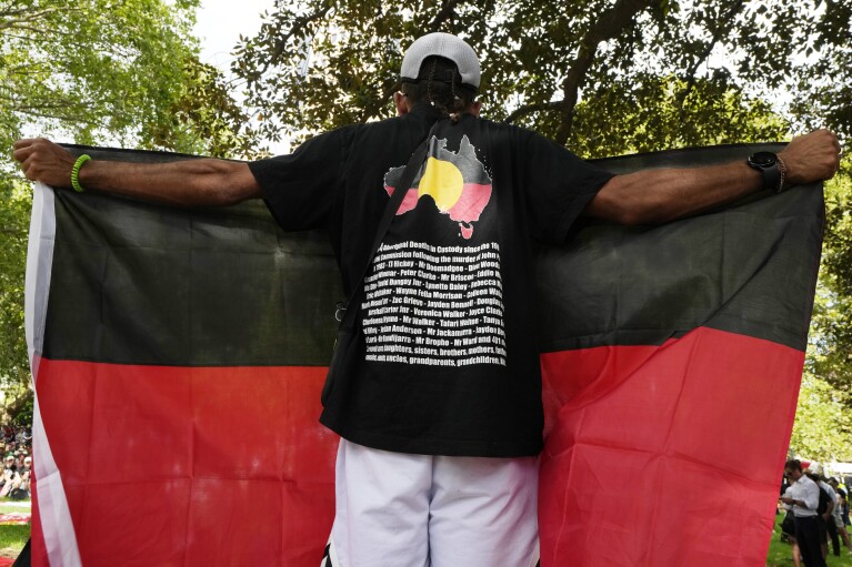 Un hombre sostiene una bandera aborigen durante una protesta del Día de Australia por parte de indígenas australianos en Sydney, el viernes 26 de enero de 2024. (Foto AP/Rick Rycroft)