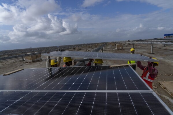 Workers install solar panels at the under-construction Adani Green Energy Limited's Renewable Energy Park in the salt desert of Karim Shahi village, near Khavda, Bhuj district near the India-Pakistan border in the western state of Gujarat, India, Thursday, Sept. 21, 2023. Led by new solar power, the world added renewable energy at breakneck speed in 2023, in an effort to turn away from fossil fuels to stave off severe Earth warming and its effects. (AP Photo/Rafiq Maqbool)