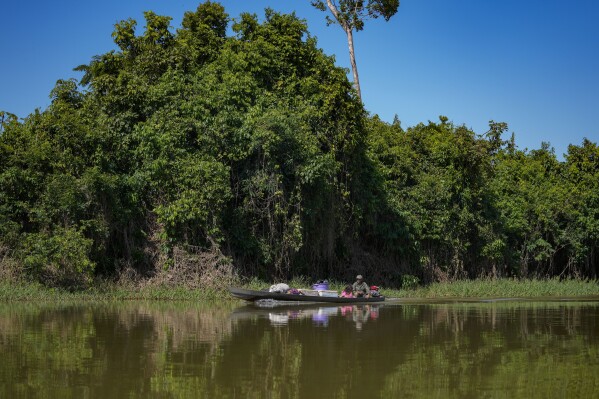 A fisherman and his daughter streer a boat on the Branco River in an extractive reserve in Jaci-Parana, Rondonia state, Brazil, Tuesday, July 11, 2023. An extractive reserve is an area in which forest communities are allowed to live their traditional ways without logging, protected from land-grabbing and cattle-ranching. (AP Photo/Andre Penner)