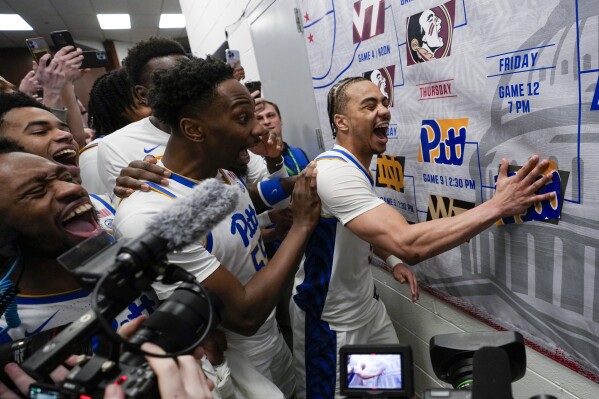 Pittsburgh guard Ishmael Leggett, right, places a decal on the bracket after an NCAA college basketball game against Wake Forest in the quarterfinal round of the Atlantic Coast Conference tournament March 14, 2024, in Washington. (AP Photo/Susan Walsh, File)