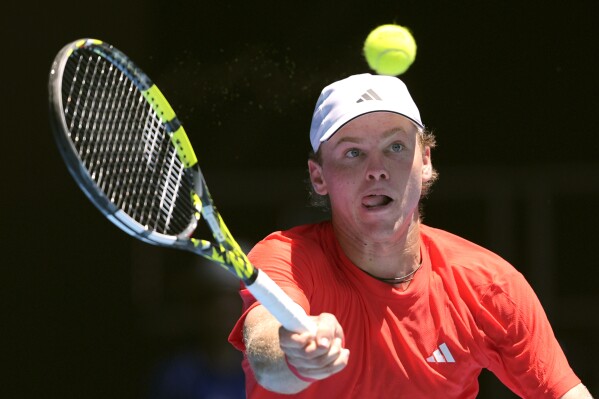 Alex Michelsen of the U.S. plays a forehand return to Stefanos Tsitsipas of Greece during their first round match at the Australian Open tennis championship in Melbourne, Australia, Monday, Jan. 13, 2025. (AP Photo/Ng Han Guan)
