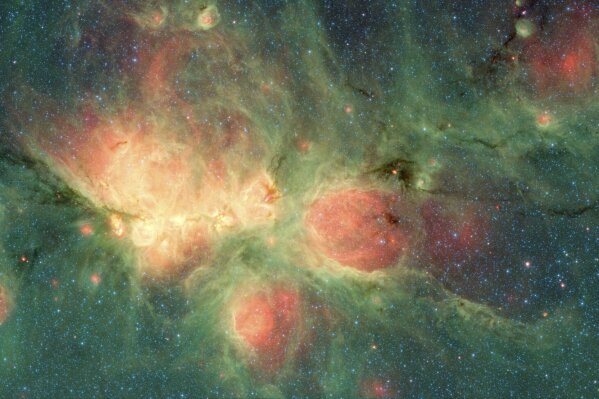 This image made available by NASA shows the Cat's Paw Nebula inside the Milky Way Galaxy located in the constellation Scorpius, captured by NASA's Spitzer Space Telescope. Its distance from Earth is estimated to be between 1.3 kiloparsecs (about 4,200 light years) to 1.7 kiloparsecs (about 5,500 light years). The bright, cloudlike band running left to right across the image shows the presence of gas and dust that can collapse to form new stars. The black filaments running through the nebula are particularly dense regions of gas and dust. The entire star-forming region is thought to be between 24 and 27 parsecs (80-90 light years) across. (NASA/JPL-Caltech via AP)