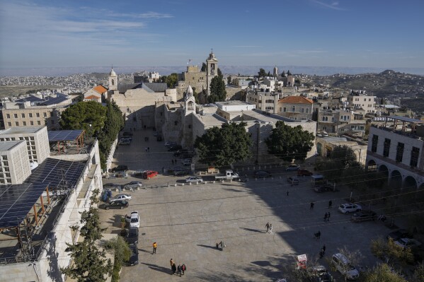 People walk in Manger Square, adjacent to the Church of the Nativity, traditionally believed to be the birthplace of Jesus Christ, in the West Bank town of Bethlehem, Saturday, Dec. 16, 2023. World-famous Christmas celebrations in Bethlehem have been put on hold due to the ongoing Israel-Hamas war. (AP Photo/Mahmoud Illean)