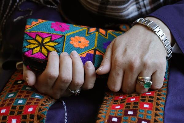 A Massachusetts resident identifying herself only as "Safi," who asked that her last name not be used for fear of retribution against her relatives in Afghanistan, holds a purse with traditional Afghan patterns, Tuesday, Nov. 9, 2021, during an interview with The Associated Press. Thousands of Afghans have applied for temporary admission into the U.S. for humanitarian reasons, but few have been approved since the Taliban recaptured control of their homeland. "We're worried for their lives," said Safi, whose family is sponsoring some 20 other relatives seeking humanitarian parole. (AP Photo/Steven Senne)