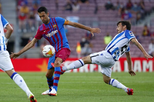 FILE - Real Sociedad's David Silva, right, fights for the ball with Barcelona's Sergio Busquets during a Spanish La Liga soccer match between Barcelona and Real Sociedad at Camp Nou stadium in Barcelona, Spain, Sunday, Aug. 15, 2021. Real Sociedad says that veteran midfielder David Silva has injured a ligament in his left knee. The club says that Silva sustained the injury to his ACL ligament during practice on Thursday, July 20, 23. (AP Photo/Joan Monfort, File)