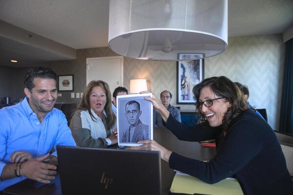 Anna Salton Eisen holds up a photo of Emil Ringel, father of Barbara Ringel, for a Zoom video call during a gathering for families of Holocaust survivors in East Brunswick, N.J., on Sunday, Sept. 26, 2021. Seventy-six years after American soldiers cut down the barbed wire and fulfilled the prisoners’ impossible dream of freedom, Eisen brought together survivors’ loved ones. (AP Photo/Brittainy Newman)