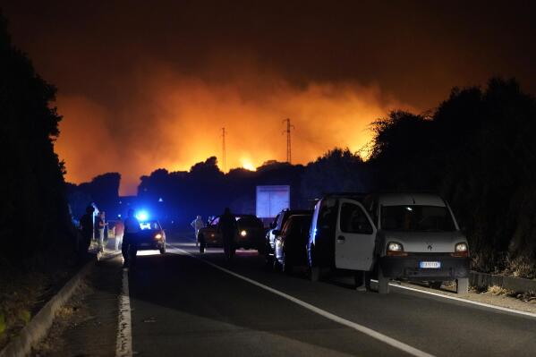 Cars are parked by the road as fires have been raging through the countryside in Cuglieri, near Oristano, Sardinia, Italy, early Sunday, July 25, 2021. Hundreds of people were evacuated from their homes in many small towns in the province of Oristano, Sardinia, after raging fires burst in the areas of Montiferru and Bonarcado. (Alessandro Tocco/LaPresse via AP)