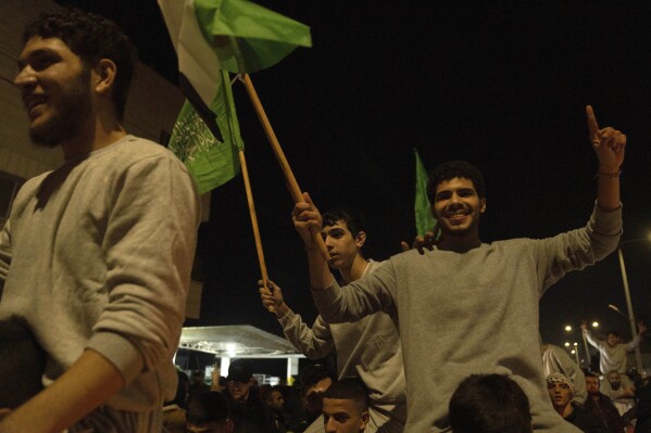 Former Palestinian prisoners who were released by the Israeli authorities, fly Palestinian and Hamas flags while they are carried on the shoulders upon their arrival in the West Bank town of Beitunia, Friday, Nov. 24, 2023. The release came on the first day of a four-day cease-fire deal between Israel and Hamas during which the Gaza militants have pledged to release 50 hostages in exchange for 150 Palestinians imprisoned by Israel. (AP Photo/Nasser Nasser)