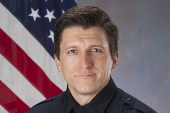 This photo provided by the Tucson, Ariz., Police Department shows Officer Adam Buckner. The Tucson police officer has died after a driver crashed into his patrol car while he was responding to a call with his siren on and lights flashing, authorities said Monday, April 1, 2024. (Tucson Police Department via AP)