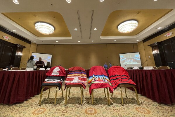 Members of the U.S. government's Not Invisible Commission prepare for a field hearing in Albuquerque, N.M. on Wednesday, June 28, 2023. Four skirts were placed at the front of the room to honor Native Americans who have gone missing or have been trafficked or killed. The commission will be crafting recommendations to improve coordination among agencies and to establish best practices for state, tribal and federal law enforcement. (AP Photo/Susan Montoya Bryan)