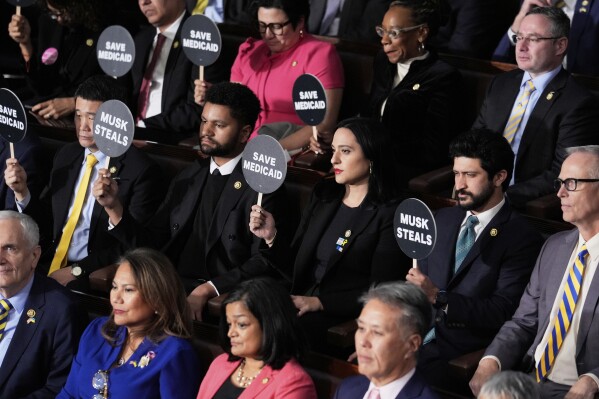 Members of Congress hold up signs as President Donald Trump addresses a joint session of Congress at the Capitol in Washington, Tuesday, March 4, 2025. (AP Photo/J. Scott Applewhite)
