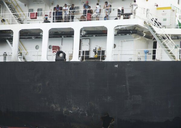 Sailors stand on deck above a hole the U.S. Navy says was made by a limpet mine on  the damaged Panama-flagged, Japanese owned oil tanker Kokuka Courageous, anchored off Fujairah, United Arab Emirates, during a trip organized by the Navy for journalists, on Wednesday, June 19, 2019. The limpet mines used to attack the oil tanker near the Strait of Hormuz bore "a striking resemblance" to similar mines displayed by Iran, a U.S. Navy explosives expert said Wednesday. Iran has denied being involved. (AP Photo/Fay Abuelgasim)