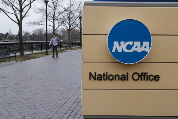 FILE - NCAA signage outside the headquarters in Indianapolis, Thursday, March 12, 2020. A settlement being discussed in an antitrust lawsuit against the NCAA and major college conferences could cost billions and pave the way for a new compensation model for college athletes. (AP Photo/Michael Conroy, File)