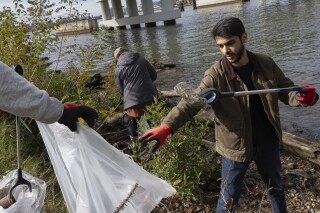 Volunteers collect trash items during a park cleanup on Wednesday, Nov. 15, 2023, at Anacostia Park in Washington. For decades, the Anacostia was treated as a municipal dumping ground for industrial waste, storm sewers and trash. That contamination largely affected the communities of color that the river intersects. (AP Photo/Tom Brenner)
