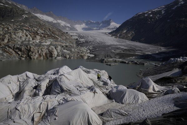 Workers prepare sheets to cover the Rhone Glacier near Goms, Switzerland, June 10, 2025. (AP Photo/Matthias Schrader)