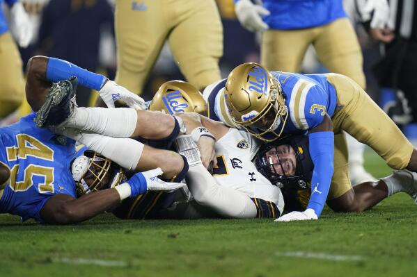 California quarterback Chase Garbers, center, is brought down by UCLA defensive back Cameron Johnson, right, and linebacker Mitchell Agude during the first half of an NCAA college football game Saturday, Nov. 27, 2021, in Pasadena, Calif. (AP Photo/Jae C. Hong)