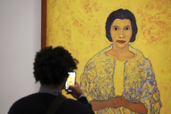 A man photographs the 1965 painting "Marian Anderson" by Beauford Delaney at the Black Paris exhibition which explores the presence and influence of about 150 Black artists in France from the 1950s to 2000 at the Pompidou Center, Monday, March 17, 2025 in Paris. (AP Photo/Nicolas Garriga)