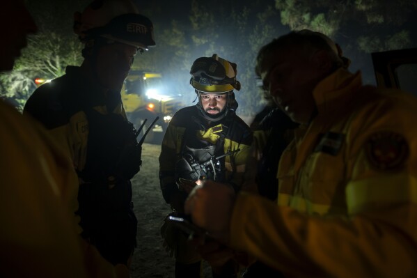 Emergency crews and firefighters work near the fire advancing through the forest toward the town of El Rosario in Tenerife, Canary Islands, Spain on Friday, Aug. 18, 2023. Officials say a wildfire is burning out of control through the Spanish Canary Island of Tenerife, affecting nearly 8,000 people who have been evacuated or ordered to stay indoors. (AP Photo/Arturo Rodriguez)