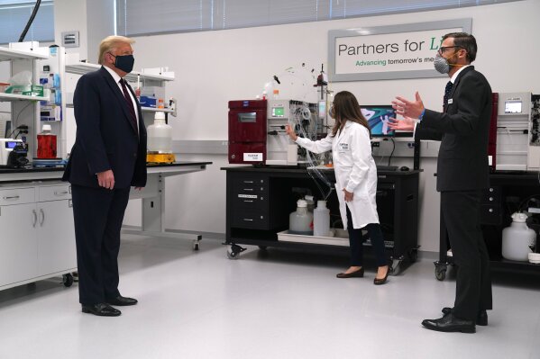 Fujifilm Diosynth Biotechnologies CEO Martin Meeson, right, speaks as President Donald Trump wears a face mask as he participates in a tour of Bioprocess Innovation Center at Fujifilm Diosynth Biotechnologies, Monday, July 27, 2020, in Morrisville, N.C. (AP Photo/Evan Vucci)