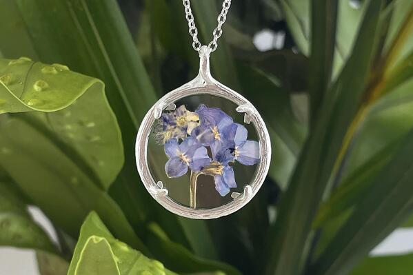 This image provided by Catherine Weitzman jewelry shows a floral necklace. Designer Catherine Weitzman says. "Nature has not only inspired my jewelry," she says. Her current collection has necklaces made of tiny alpine flowers captured in glass; earrings, cast in gold vermeil or recycled silver, of fan coral found on island beaches; and pendants of fern from the forest floor, also cast in metal. Weitzman thinks biophilia is trending because the idea of being surrounded by nature and connecting with others enhances "mood, productivity and creativity, while reducing stress. The world needs a nice boost of all those things right now." (Catherine Weitzman jewelry via AP)