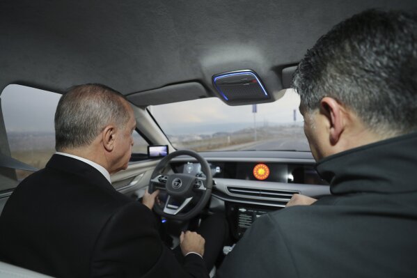 Turkish President Recep Tayyip Erdogan drives a prototype of a domestically produced electric car, in Gebze, Turkey, Friday, Dec. 27, 2019. Turkey's president has unveiled prototypes of what he hopes will be the country's first domestically produced car. In a ceremony on Friday, Recep Tayyip Erdogan showcased the SUV and sedan models of the electric automobile, known for now as TOGG after the Turkish consortium that plans to produce the vehicles. (Presidential Press Service via AP, Pool)