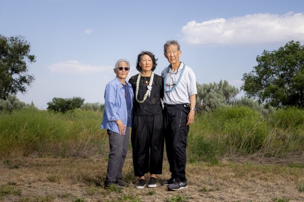 Minidoka Pilgrimage co-chair Erin Shigaki, center, poses with parents Polly Shigaki, left, and John Shigaki, right, at Minidoka National Historic Site, Saturday, July 9, 2023, in Jerome, Idaho. John was born at Minidoka, delivered by a horse veterinarian, while Polly, whose parents were matched and married there, was born in Cleveland after they left camp. "I think the pilgrimage is just so important for people to be able to to grapple with the questions that they have...And for it to be a safe place to ask and wonder and have these emotions and and therefore heal," Erin Shigaki said. (AP Photo/Lindsey Wasson)