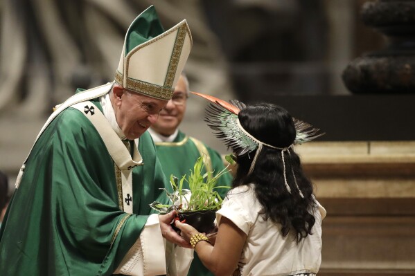 An Amazon Indigenous girl gives Pope Francis a plant during the offertory of a Mass for the closing of Amazon synod in St. Peter’s Basilica at the Vatican, Oct. 27, 2019. (AP Photo/Alessandra Tarantino)